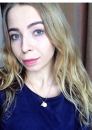 girl-blue-eyes-with-gold-amulet-before-window-blond-in-blue-sweater